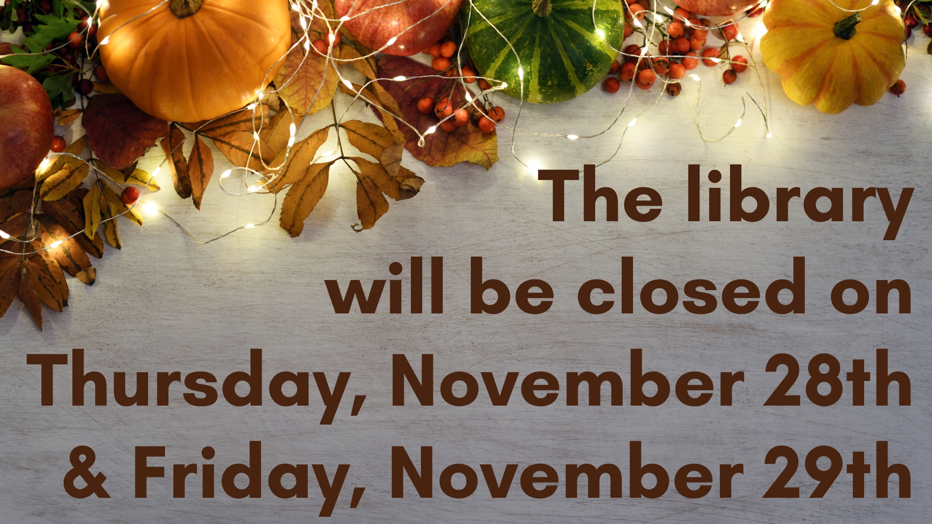 Multicolored pumpkins in the upper left hand corner with a strand of white lights laid upon them on a bed of brown leaves and red berries with the phrase The library will be closed on Thursday, November 28th and Friday, November 29th written below it.